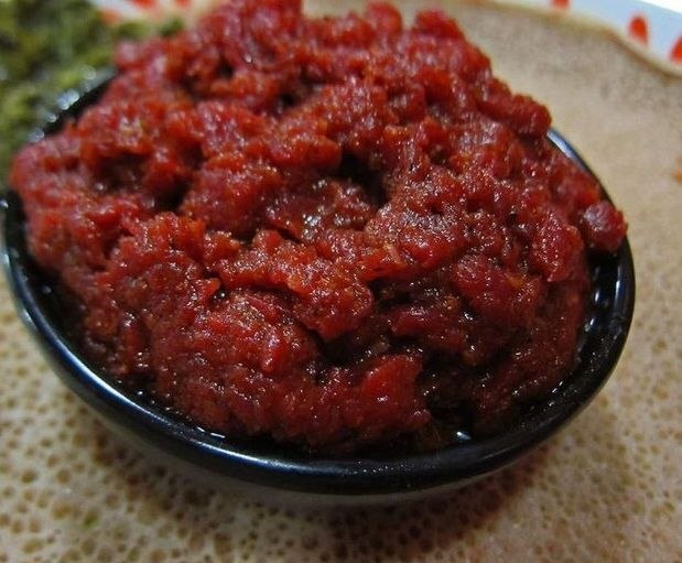 Dullet minced meat served in a black bowl on injera